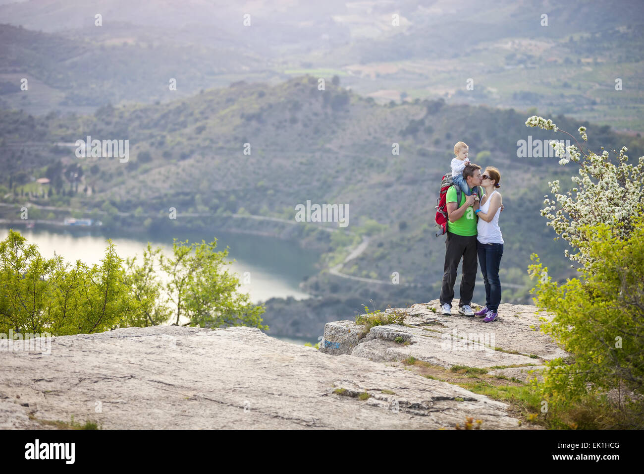 Jeune couple avec bébé garçon debout sur la falaise et les baisers Banque D'Images