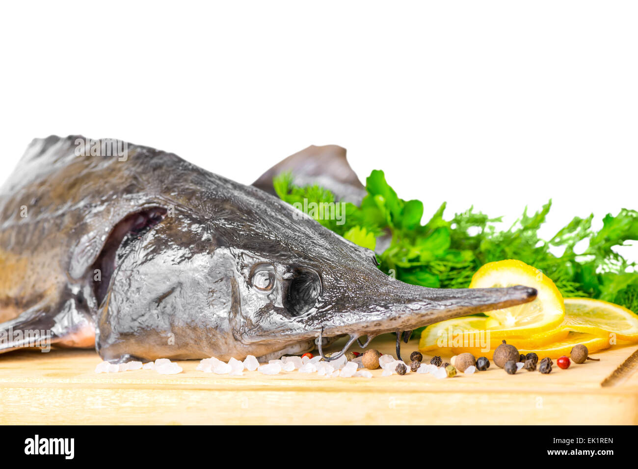 Matières premières fraîches poisson esturgeon avec verts, citron, sel et piments différents, isolé sur fond blanc, gros plan Banque D'Images