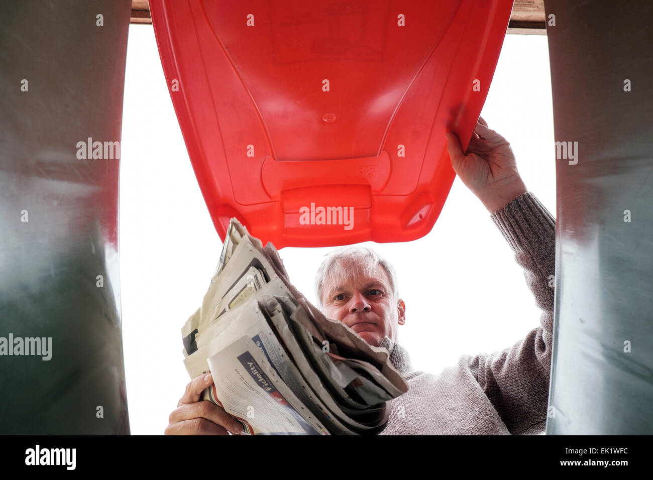 Man dropping journal dans bac de recyclage des déchets ménagers Banque D'Images