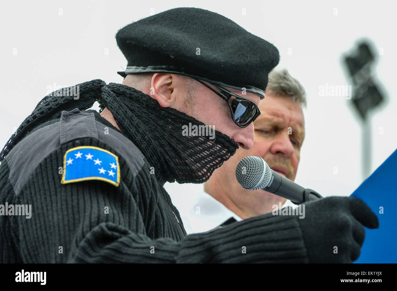 Belfast, en Irlande du Nord, Royaume-Uni. 5 avril, 2015. Un homme portant un uniforme paramilitaire noir, y compris des lunettes noires, écharpe et béret, lit le tableau d'honneur de l'Armée de libération nationale irlandaise interdits Crédit : Stephen Barnes/Alamy Live News Banque D'Images