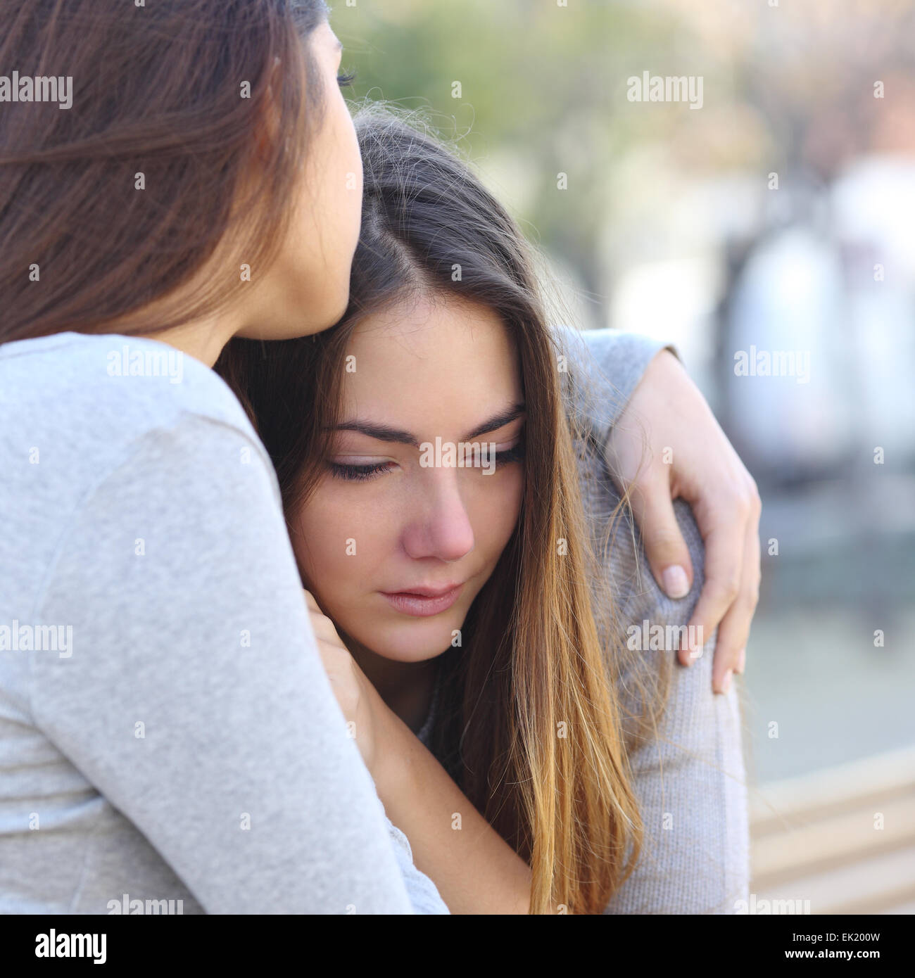 Sad girl crying et un ami réconfortant à l'extérieur dans un parc Banque D'Images