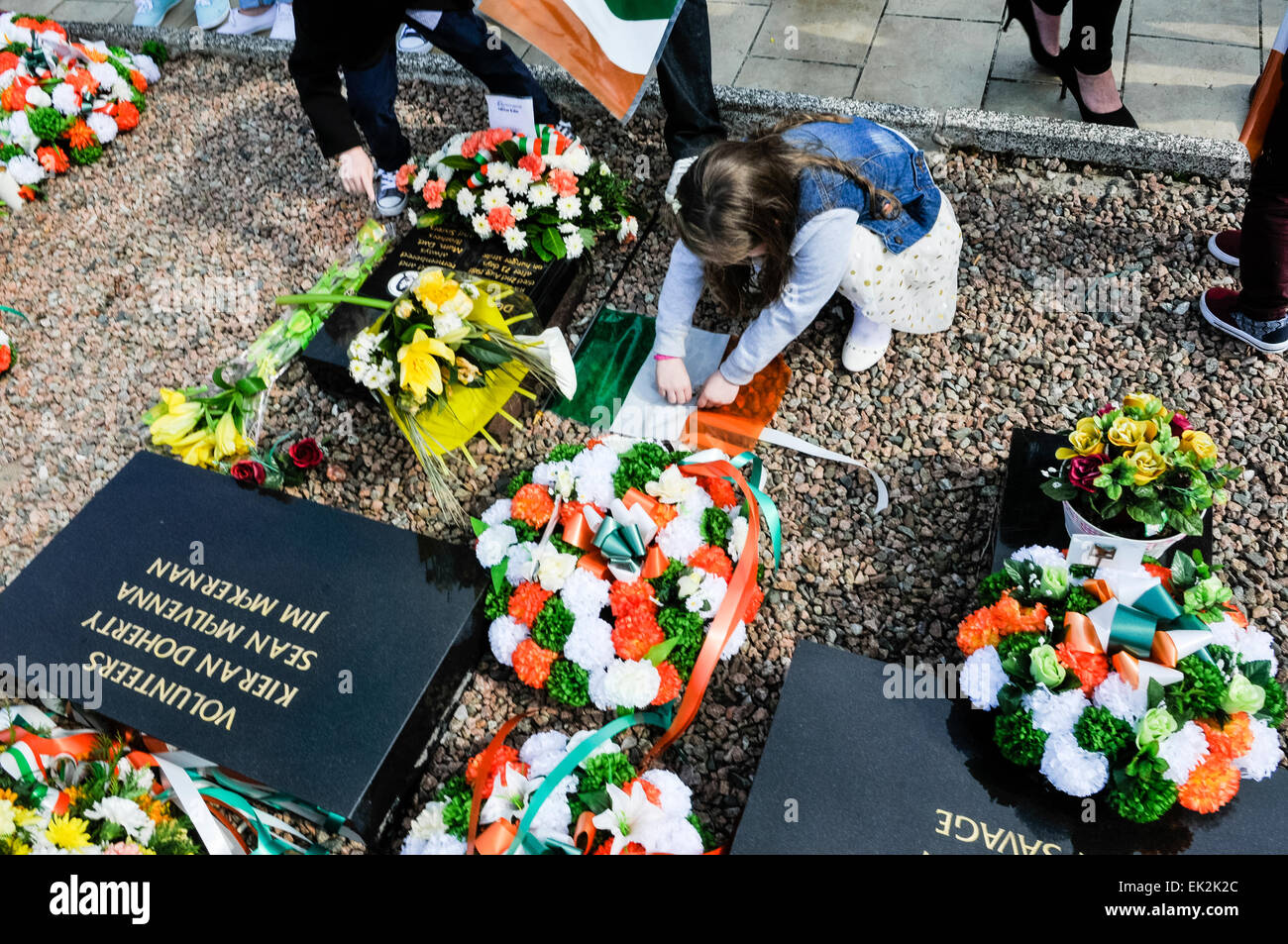 Une jeune fille dépose une couronne à l'IRA en parcelle républicaine Cimetière Milltown, Belfast Banque D'Images