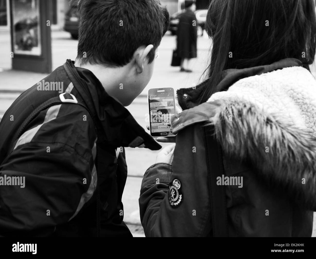 Allemagne Munich 2 school boy et girl gossip en smartphone réseau social Banque D'Images