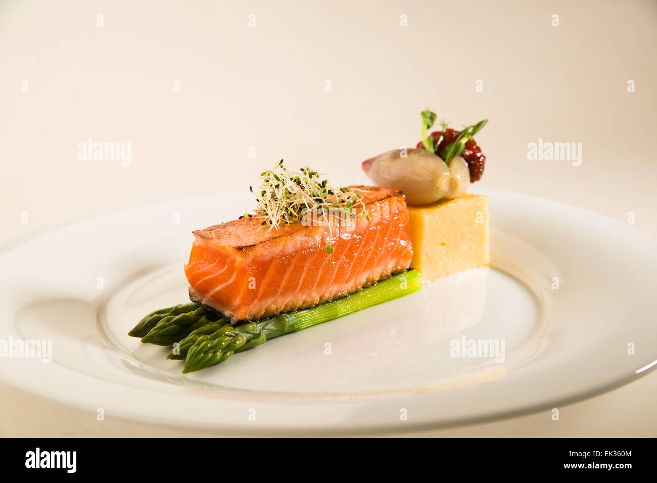 Un morceau de saumon poêlé, asperges, maïs bouillie sur une plaque blanche Banque D'Images