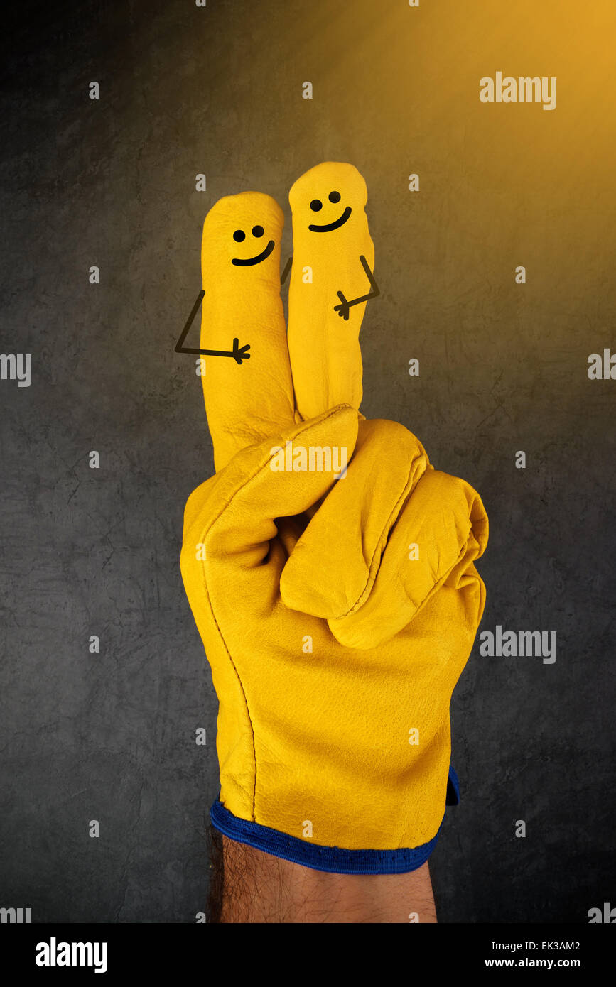 Deux heureux rire emoticons sur des doigts de cuir jaune Gants de travail de protection de l'industrie de la Construction Banque D'Images Deux heureux rire emoticons sur des doigts de cuir jaune Gants de travail de protection de l'industrie de la Construction Banque D'Images