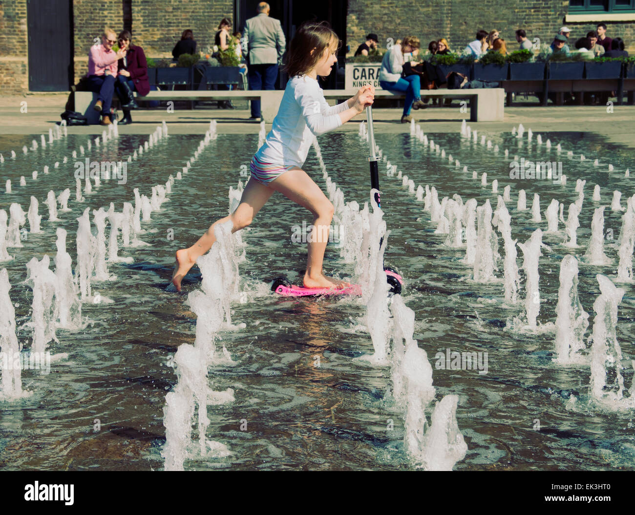 Enfant à jouer dans la fontaine d'eau dans le grenier Sq dans le nouveau NC1 develpoment Kings Cross London UK Banque D'Images