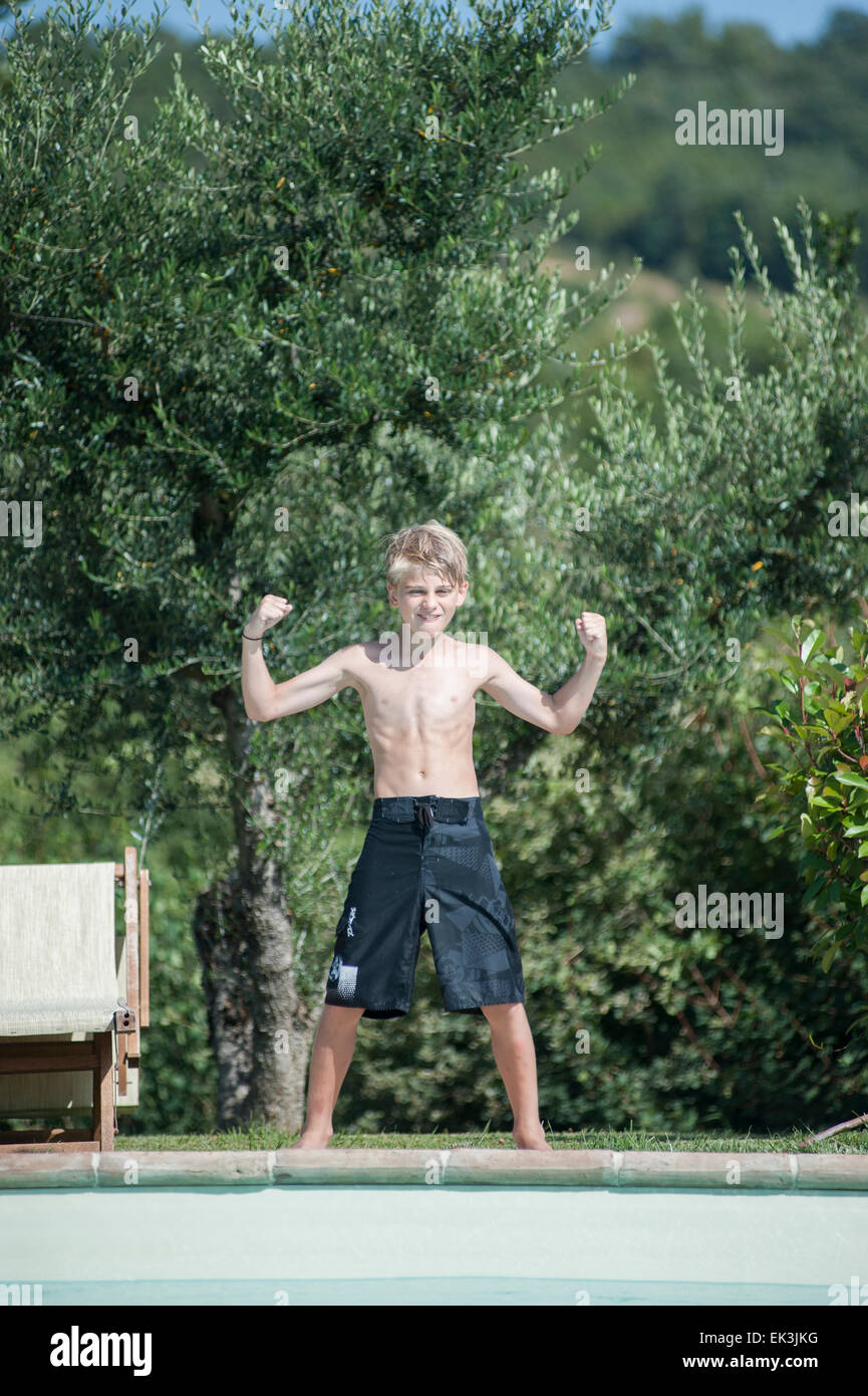 Un jeune garçon en maillot de bain noir pose de la piscine en vacances Banque D'Images