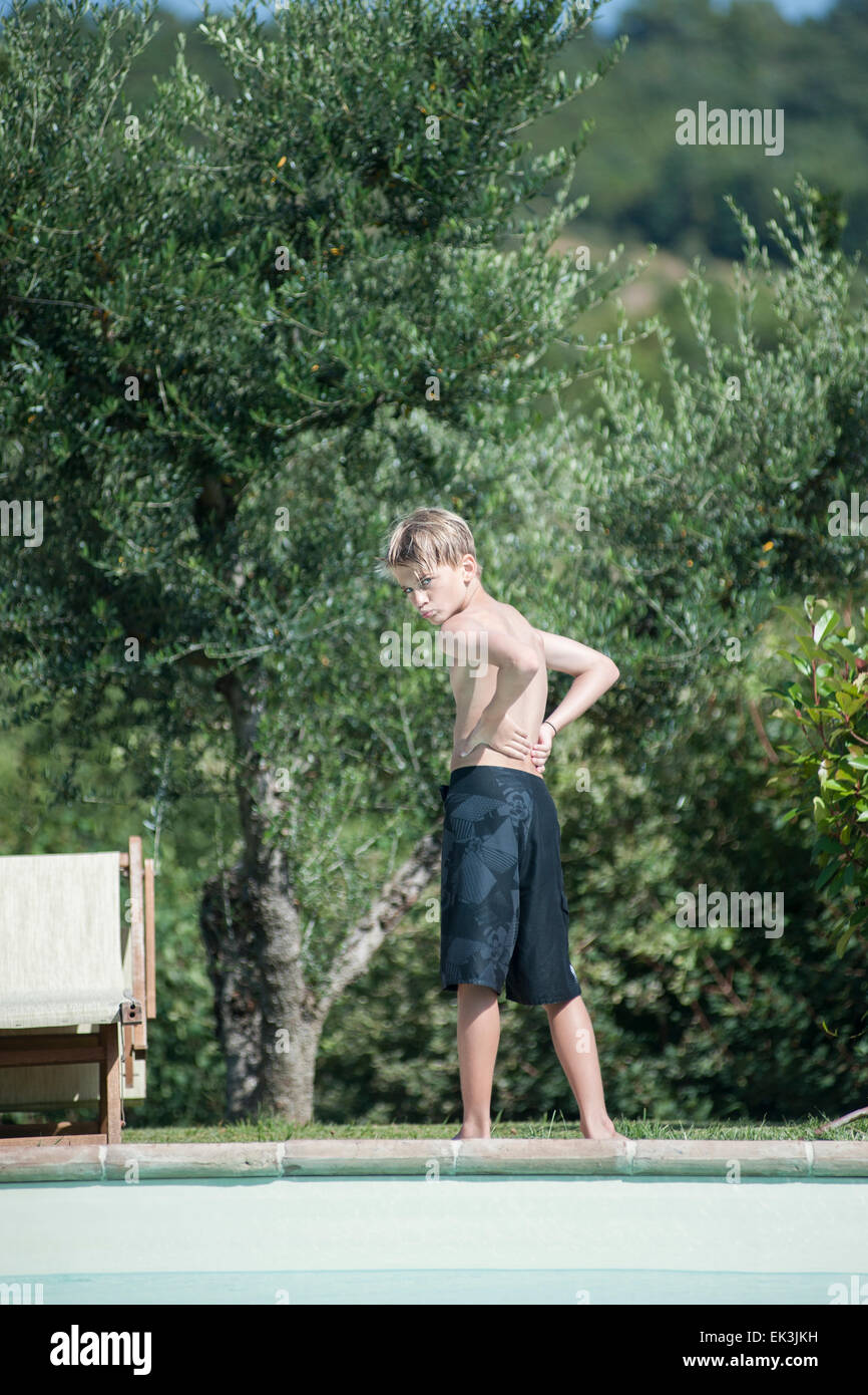 Un jeune garçon en maillot de bain noir pose de la piscine en vacances Banque D'Images