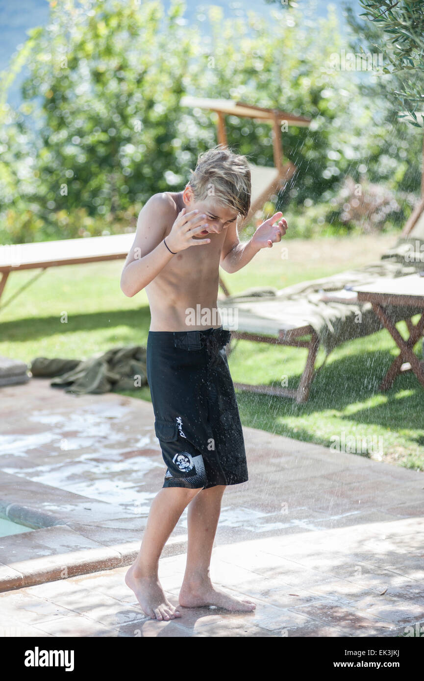 Un jeune garçon en maillot de bain noir danses par la piscine en vacances Banque D'Images