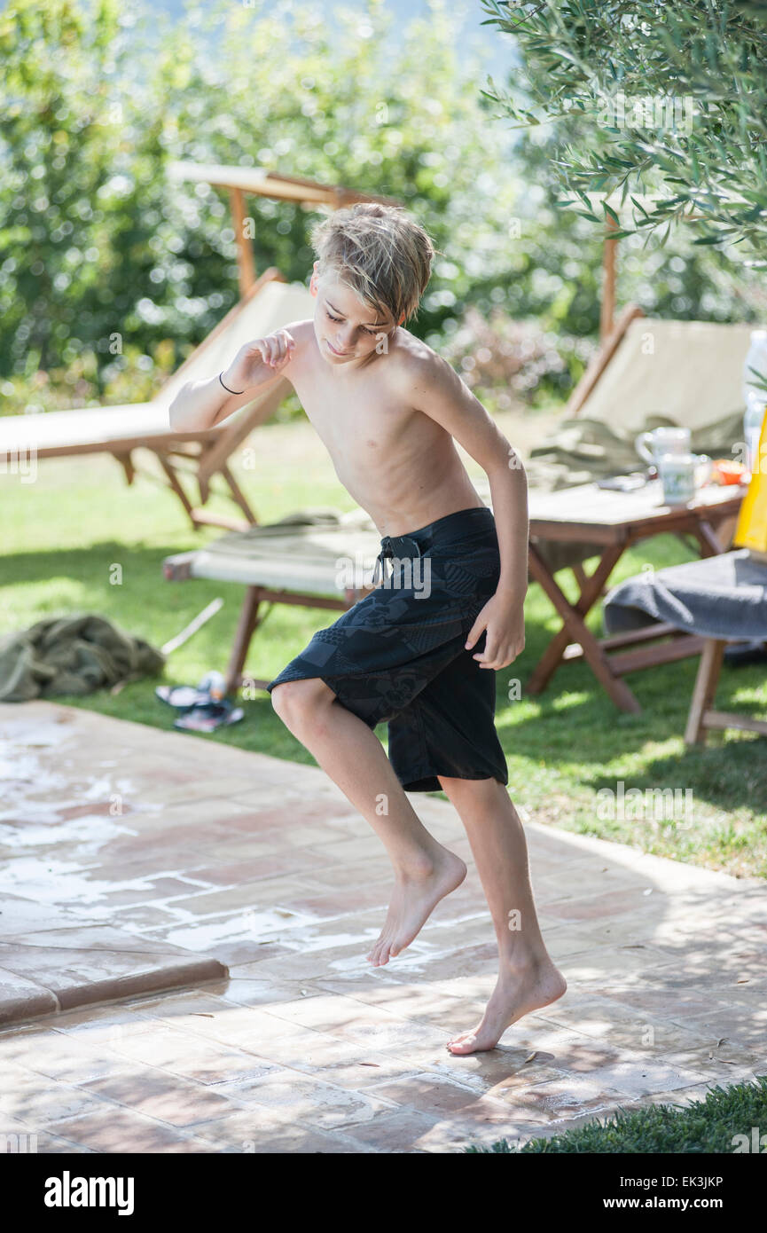 Un jeune garçon en maillot de bain noir danses par la piscine en vacances Banque D'Images