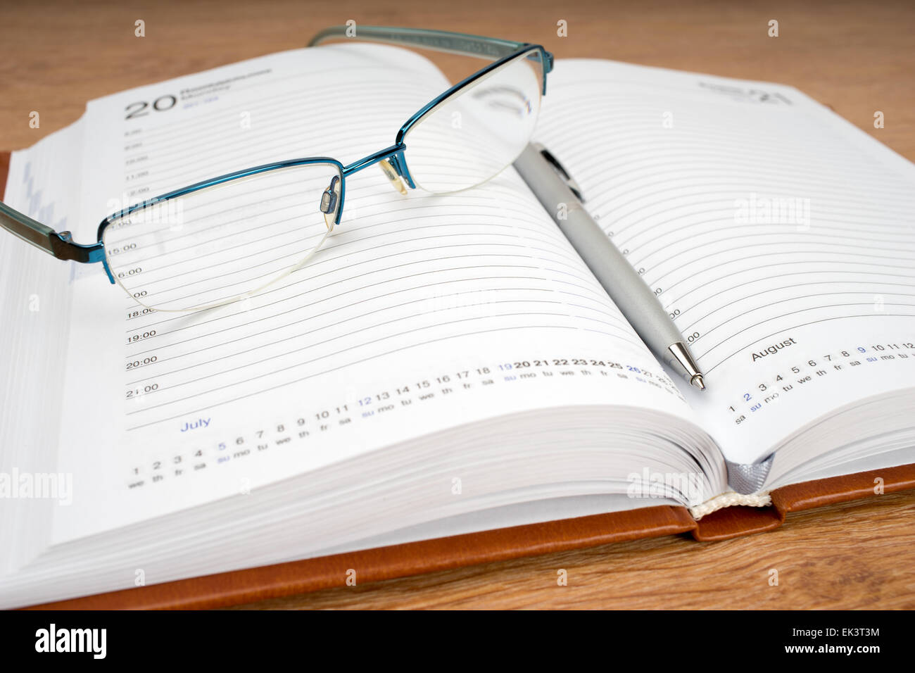 Planificateur quotidien avec des lunettes et un stylo sur la table Banque D'Images