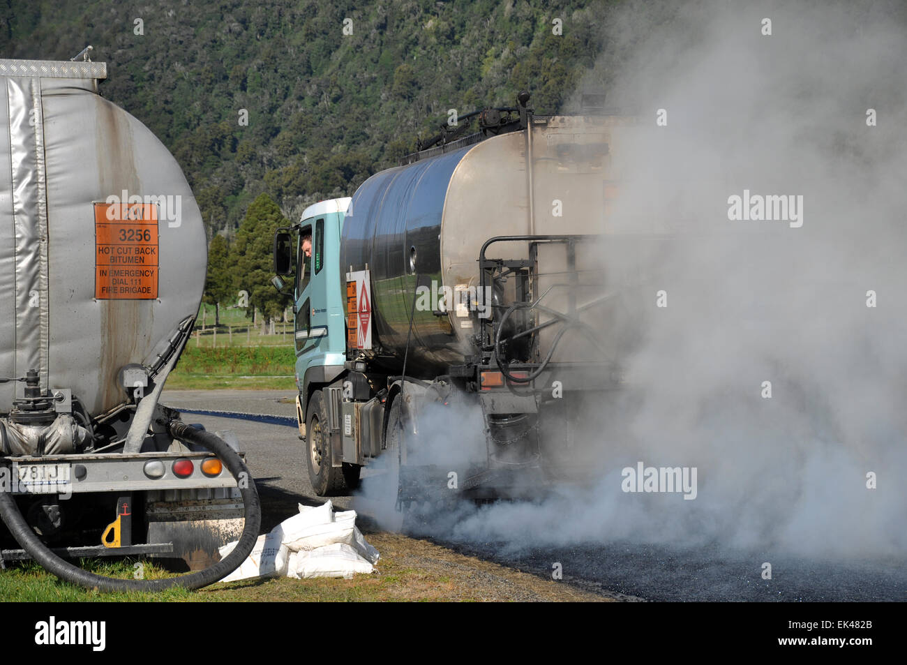 Un pétrolier s'étend du bitume chaud tout en tarsealing une bande d'air privé près de Greymouth, Nouvelle-Zélande Banque D'Images