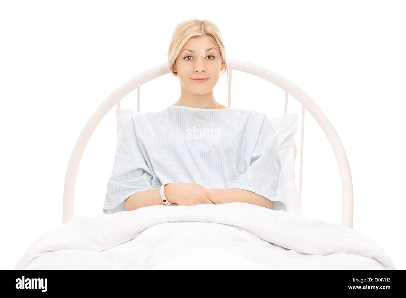 Belle jeune femme couchée dans un lit d'hôpital et posant isolé sur fond blanc Banque D'Images