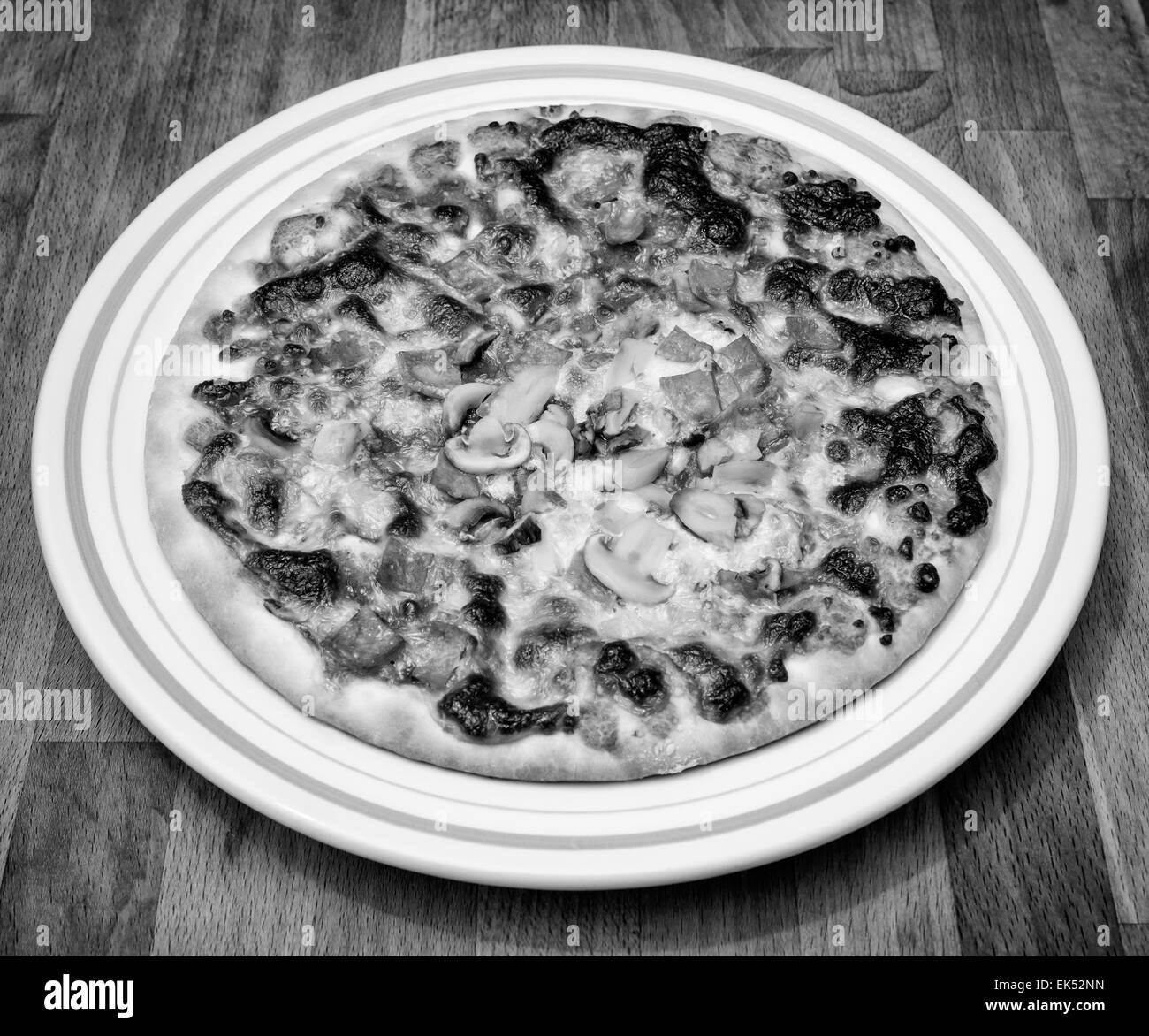 La nourriture, la pizza italienne avec tomates, mozzarella, jambon et champignons sur une table en bois Banque D'Images
