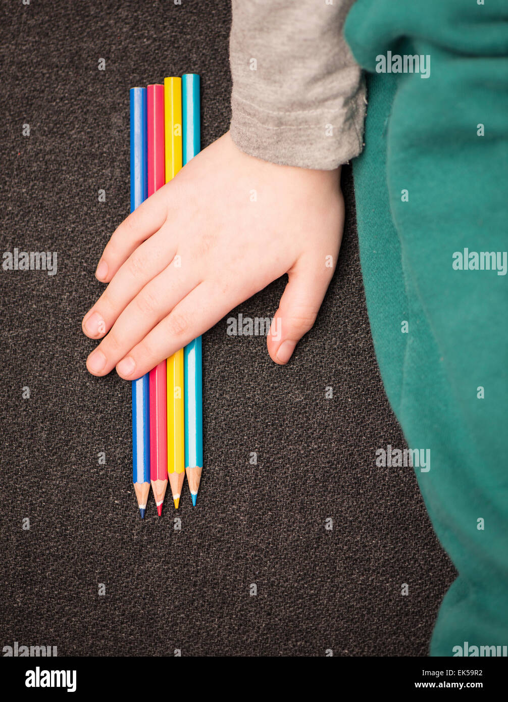 Little girl holding main au-dessus de crayons colorés. Banque D'Images