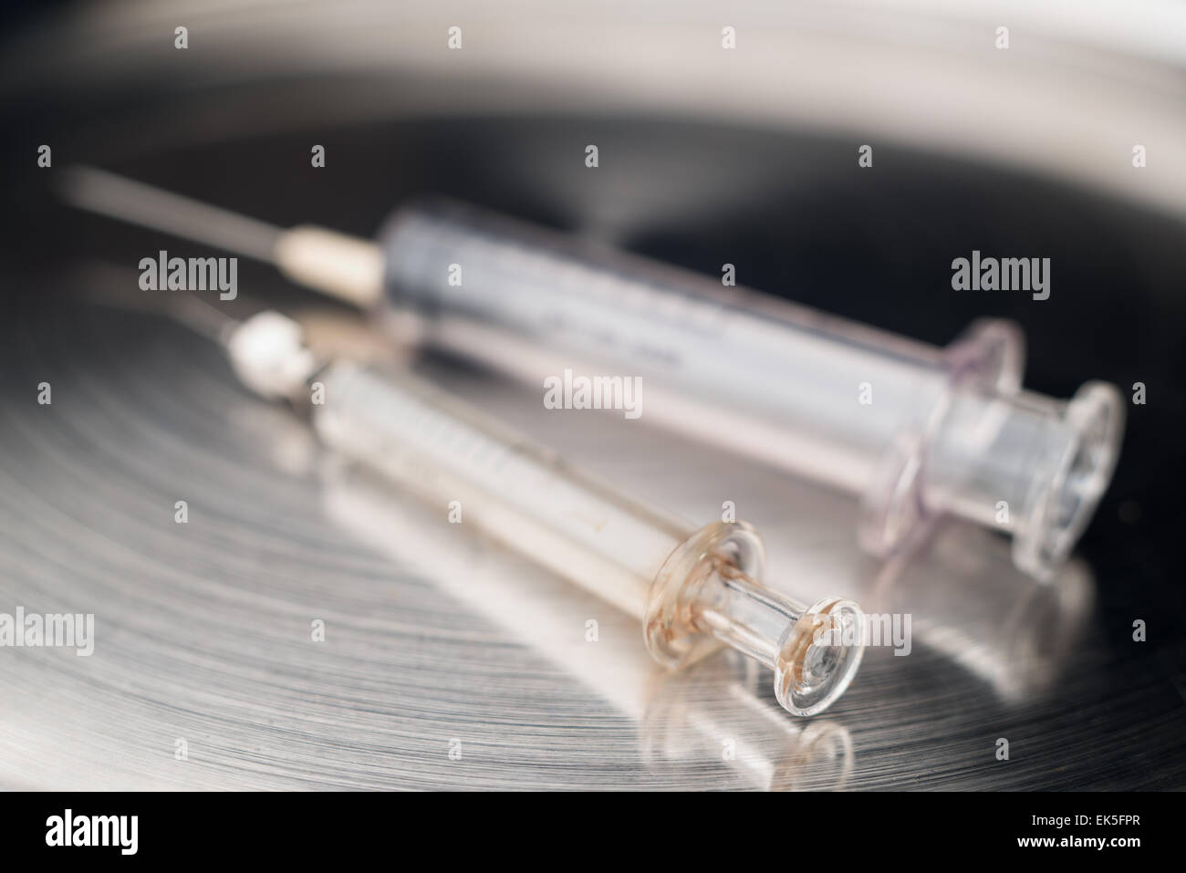 Deux seringues différents types de verre et de plastique avec des aiguilles hypodermiques stériles sur bac acier inoxydable médical poli Banque D'Images