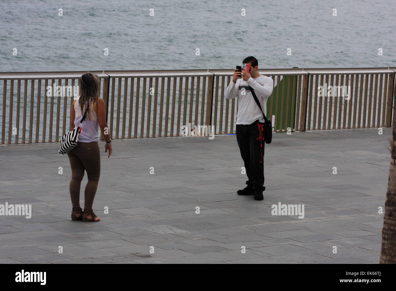 L'homme prend photo d'une jeune fille par la mer Méditerranée à Barcelone, Catalogne, Espagne, août 2014 Banque D'Images