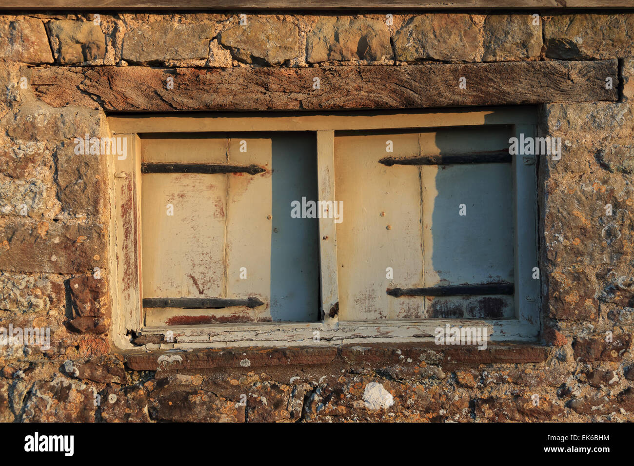Vieille fenêtre en décomposition dans la grange avec mur de pierre. Banque D'Images