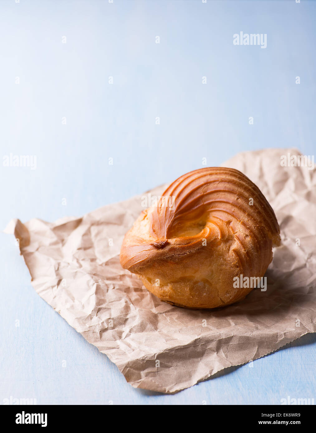 Pâte à choux crème pâtissière avec anneau eclair sur fond bleu, selective focus Banque D'Images