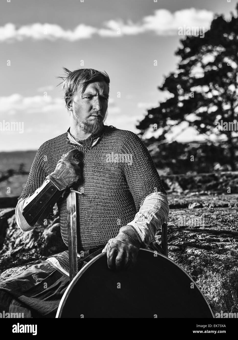 Guerrier viking médiéval portant des cottes de mailles, il a l'épée et le bouclier, sur la nature du fond, image en noir et blanc Banque D'Images