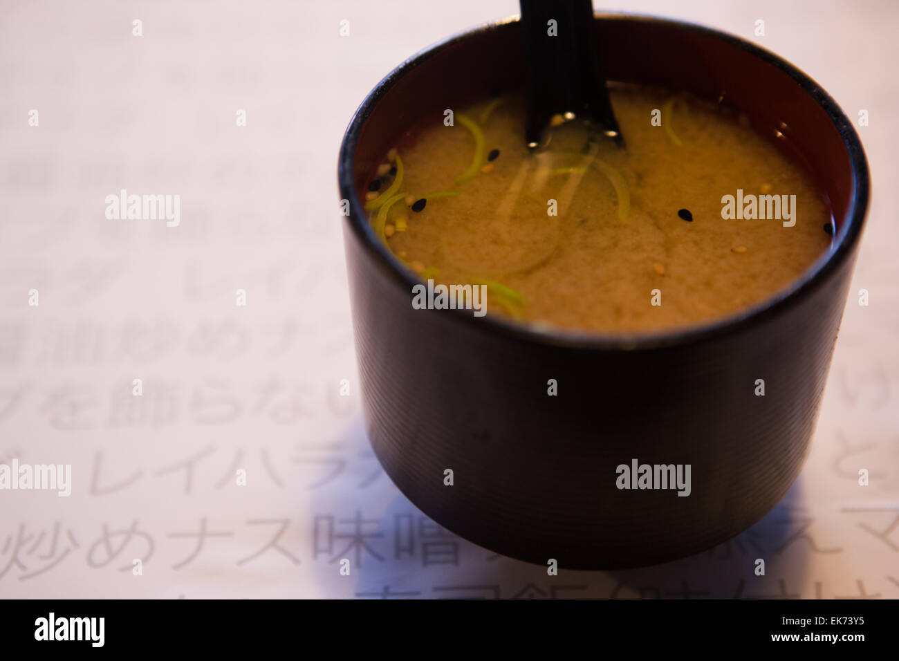 Un gros plan d'un noir et rouge bol avec de délicieux soupe miso et cuillère Banque D'Images