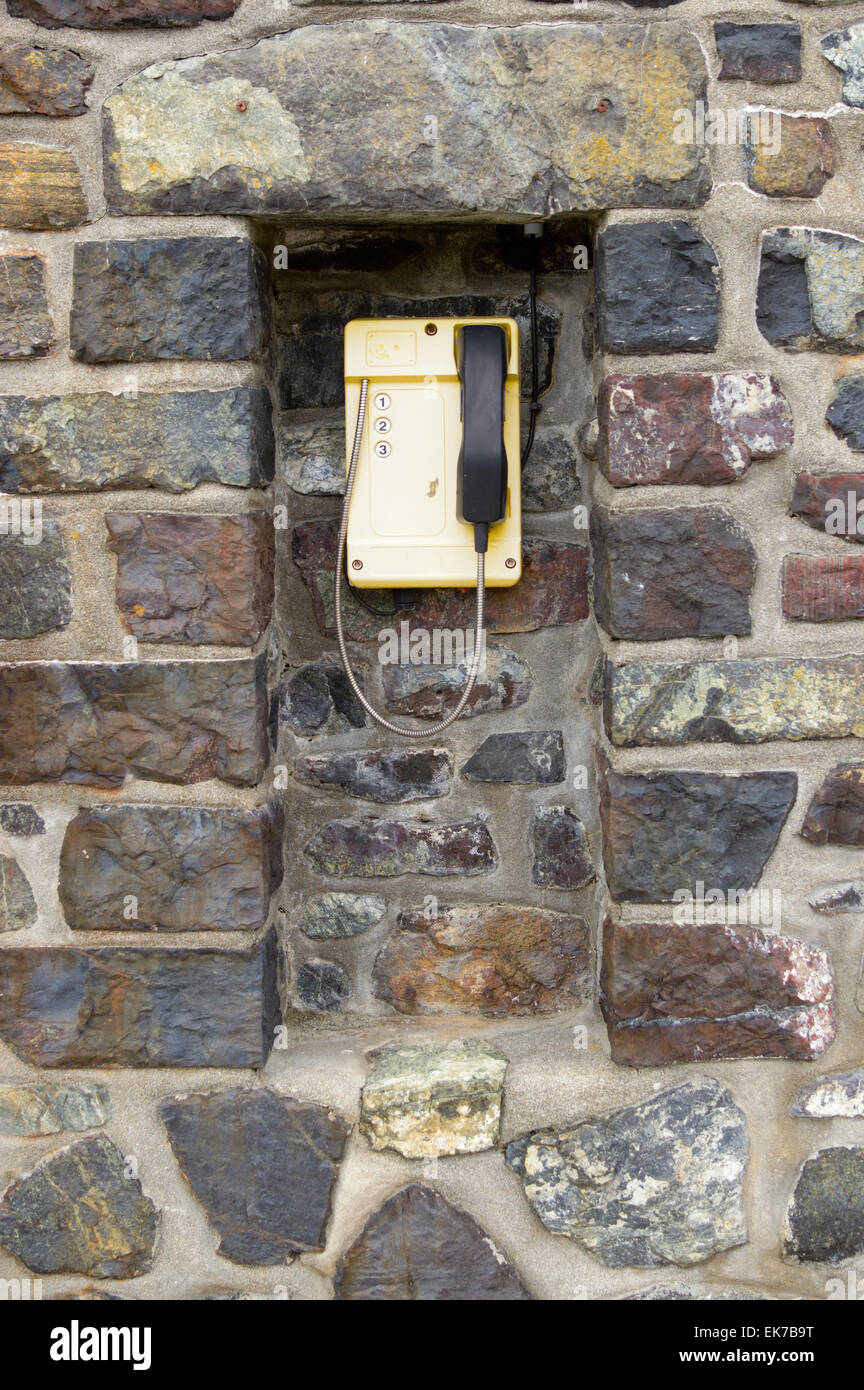 Téléphone en plastique jaune avec trois numéros à appeler au garde-côtes meneau harbour, meneau, Cornwall, Angleterre Banque D'Images