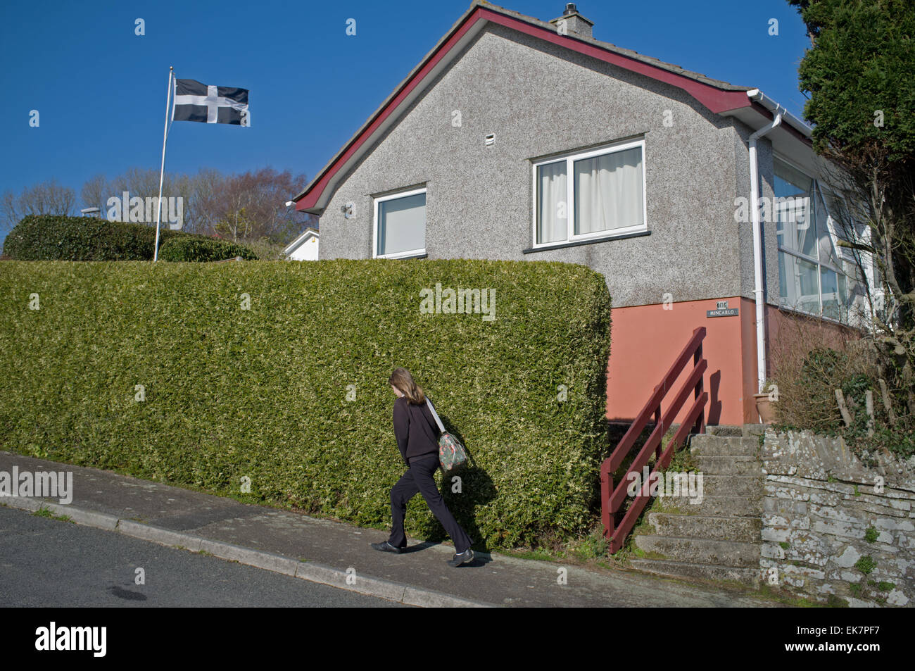 Un enfant passe devant une maison avec un drapeau cornish dans le jardin Banque D'Images