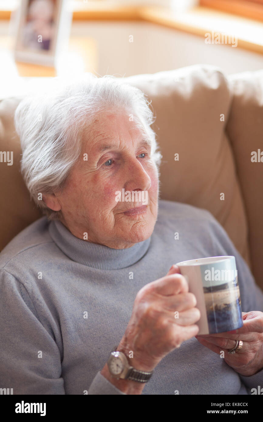 Vieille dame se détend dans un fauteuil avec une tasse de thé Banque D'Images