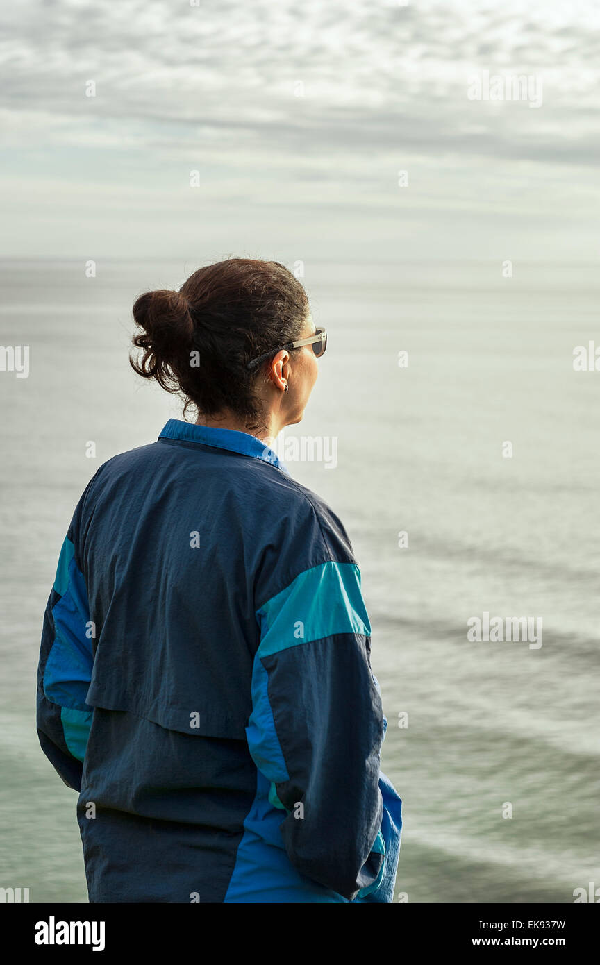 Femme adulte solitaire apprécie l'océan surise. Banque D'Images