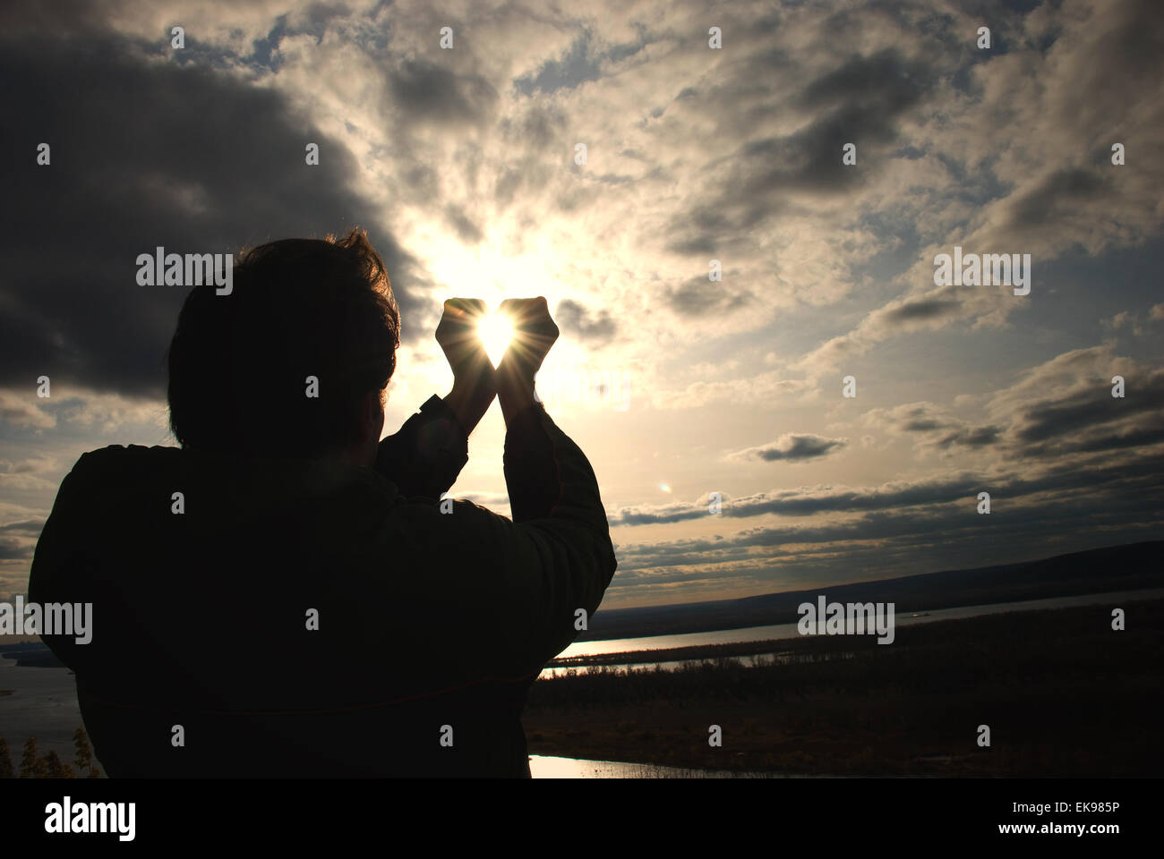 Homme tenant un soleil dans ses mains contre le ciel Banque D'Images