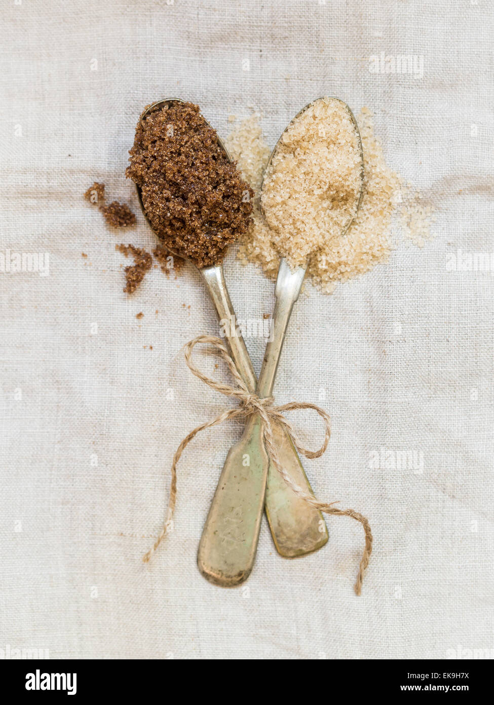 Muscovado et demerara sucres bruns sur deux cuillères en argent placé sur une nappe de lin rustique. Orientation verticale. Banque D'Images