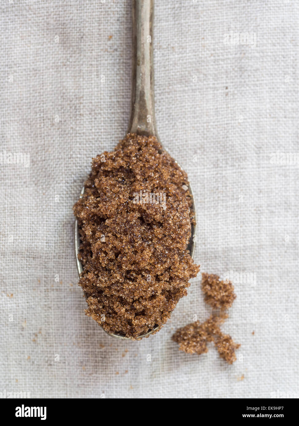 Muscovado sucre brun sur une cuillère en argent placé sur une nappe de lin rustique, Close up. Orientation verticale. Banque D'Images