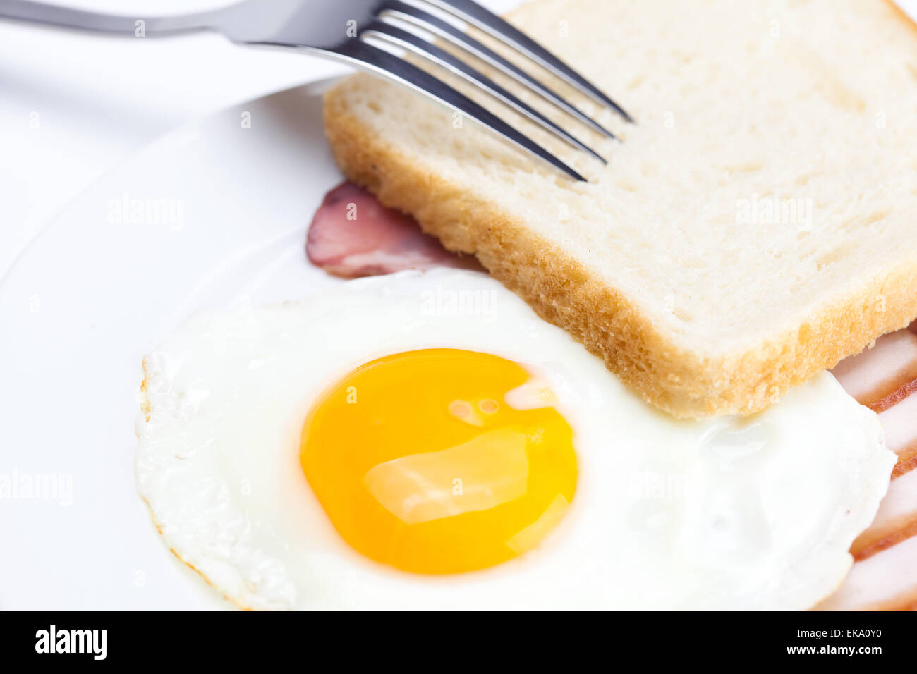 Avec les œufs au bacon dans une assiette, fourchette et pain isolé sur w Banque D'Images