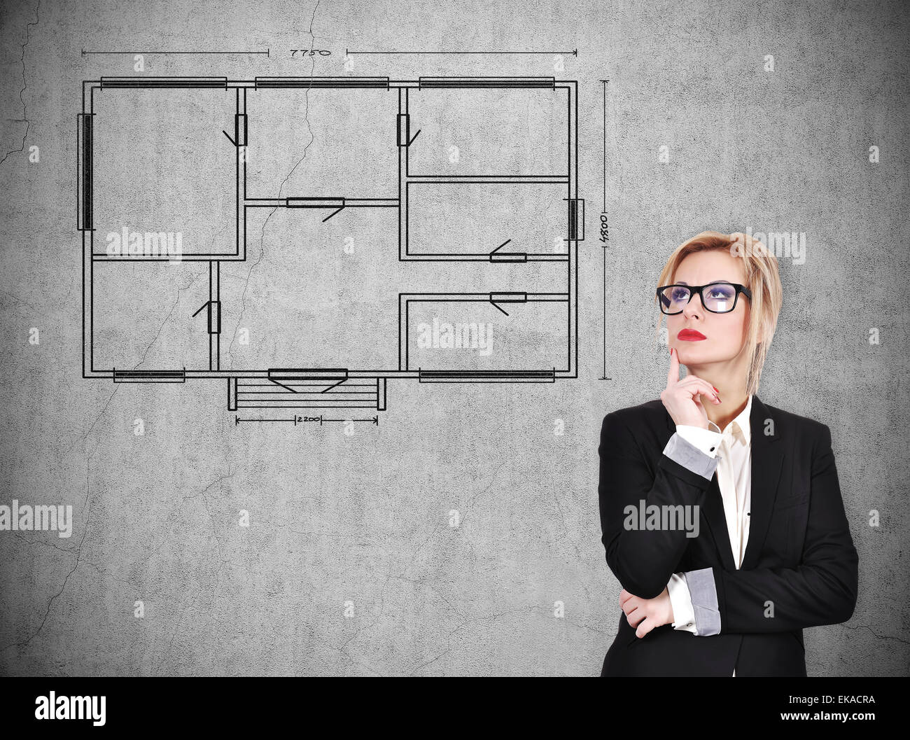 Businesswoman thinking et à la recherche sur blueprint sur mur de béton Banque D'Images