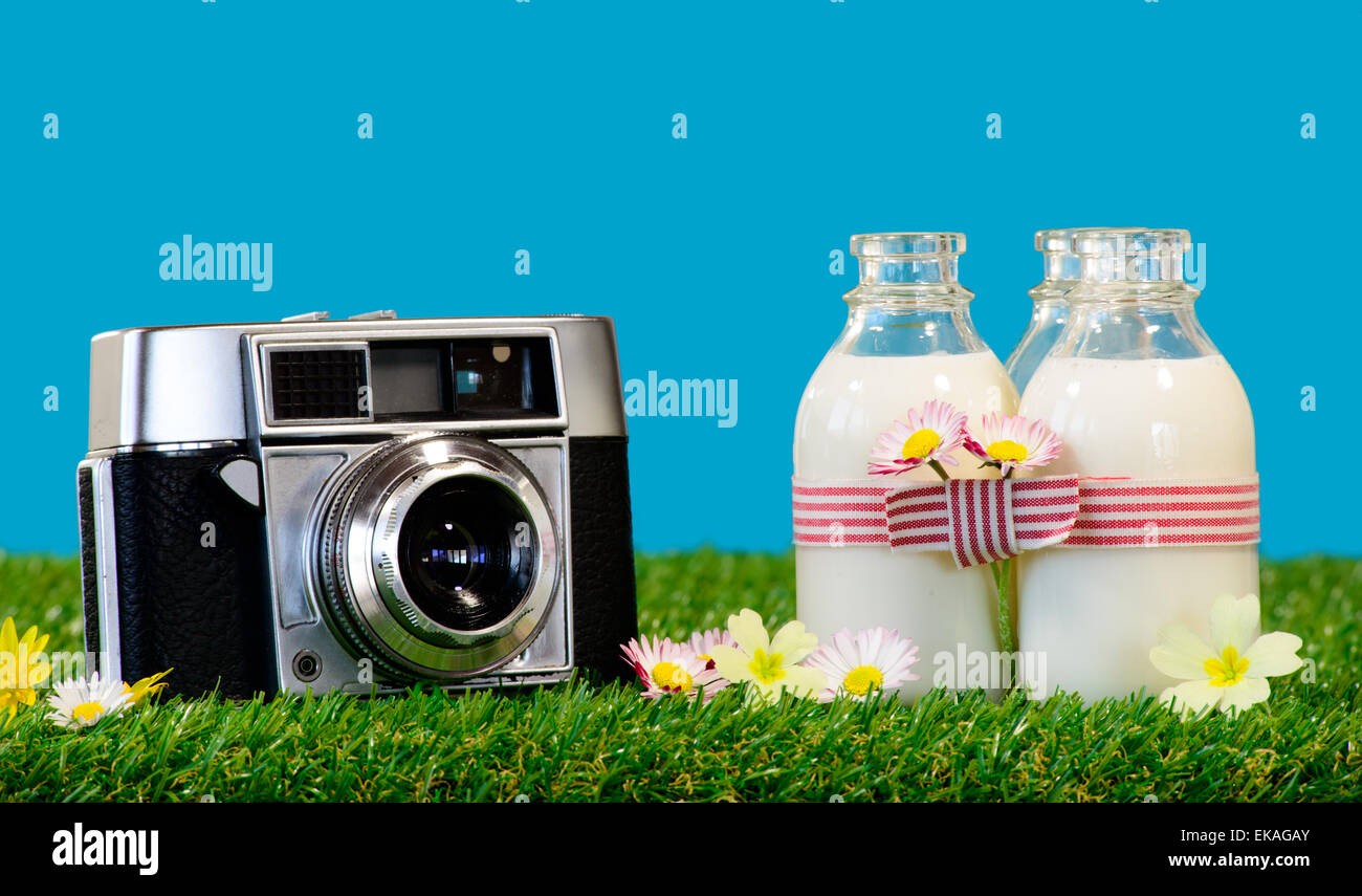 Trois petites bouteilles de lait avec un appareil photo dans l'herbe Banque D'Images