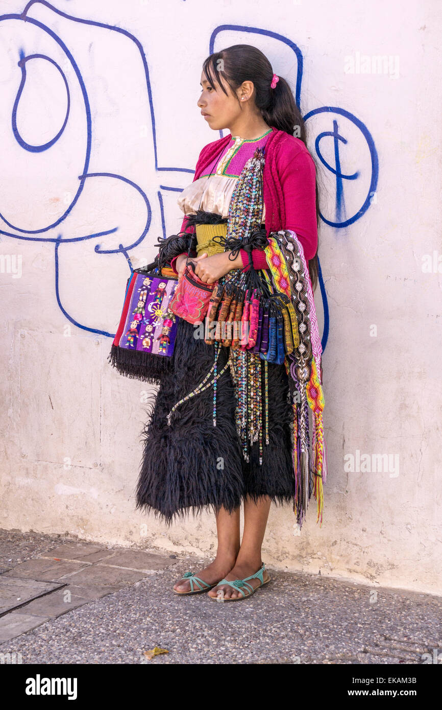 Belle indienne Tzotzil autochtone permanent adolescent contre mur blanc avec textile vente grafitti San Cristobal de las Casas Banque D'Images