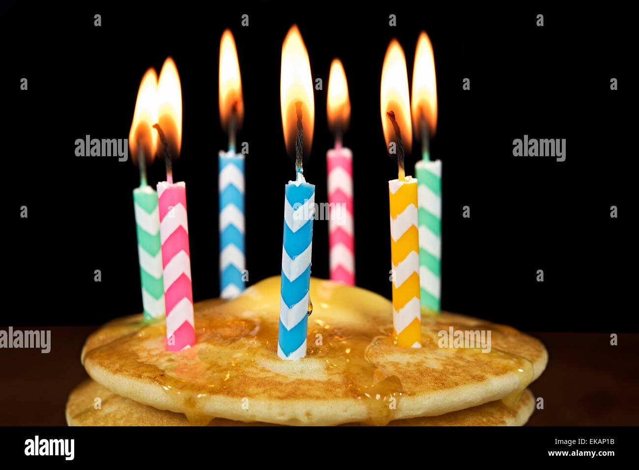 Bougies d'anniversaire Chevron sur pile de crêpes à faire fondre le beurre et le sirop. Banque D'Images