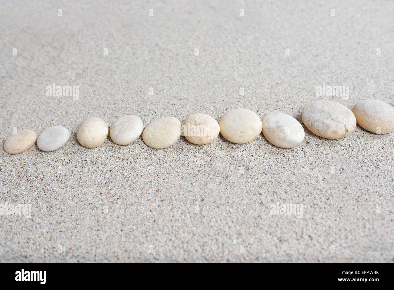 Quelques pierres disposées sur le sable de la plage avec un arrière-plan lumineux Banque D'Images