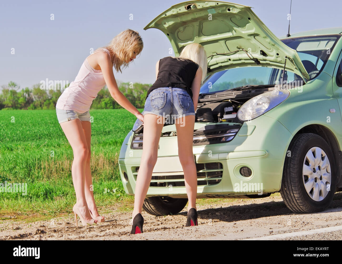 Deux blondes debout près de la voiture cassée Banque D'Images