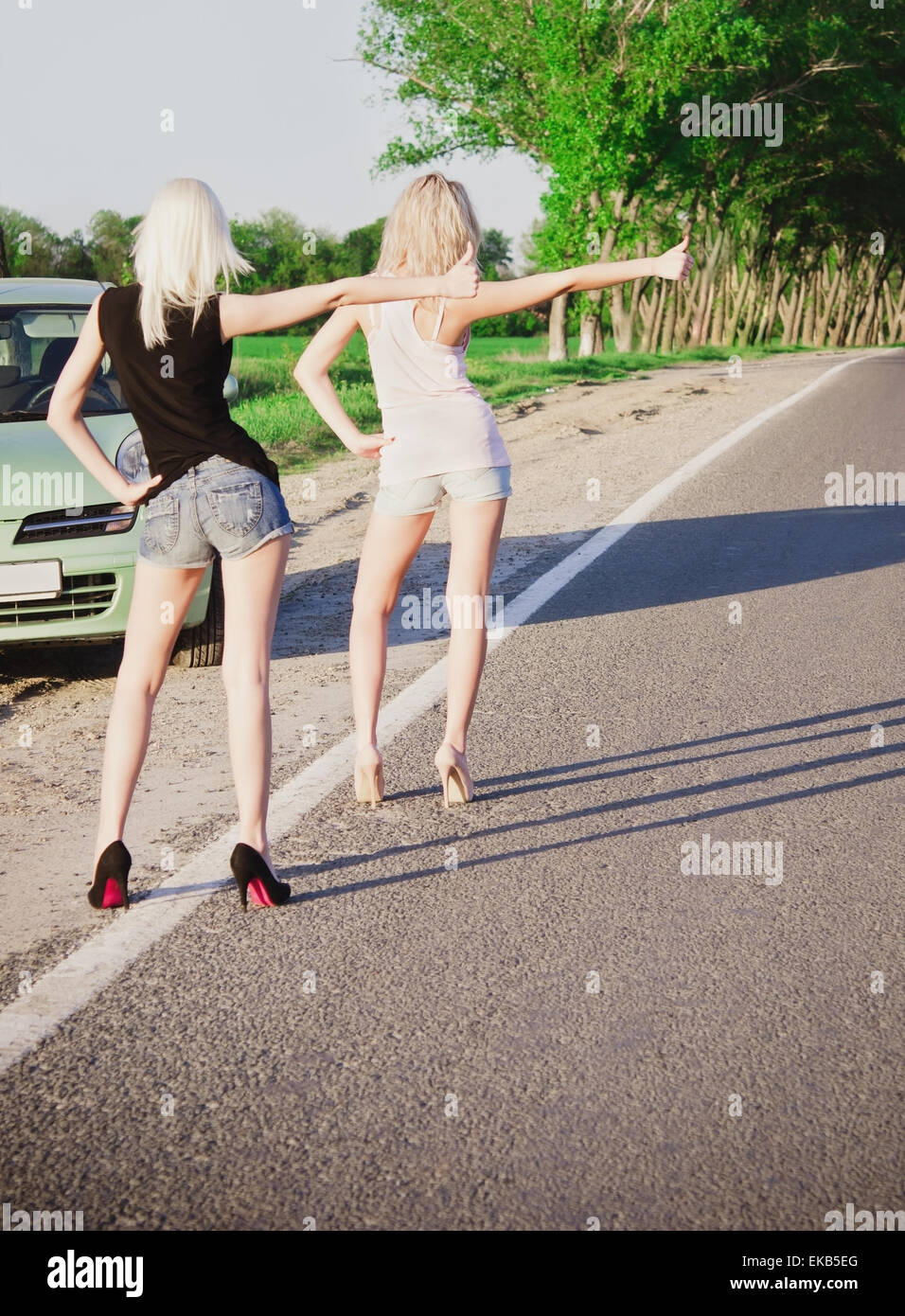 Deux filles sexy blonde debout près de leur voiture cassée et l'auto-stop Banque D'Images