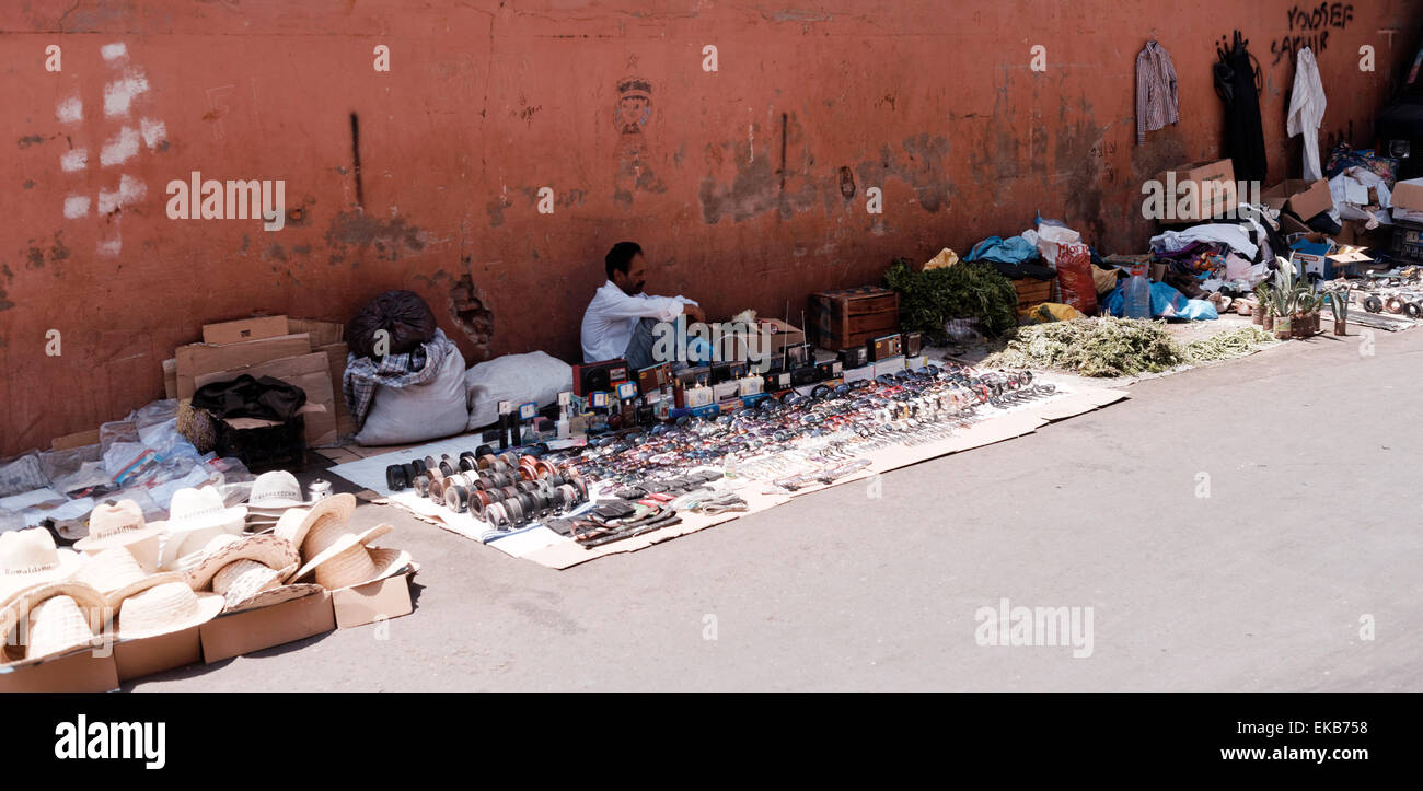 Les vendeurs de rue ambulants sans cale dans le souk de Marrakech vieille ville bordée par le mur avec des marchandises sur couverture sur le sol. Banque D'Images