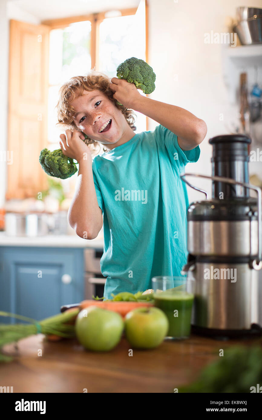 Teenage boy playing with broccoli in kitchen Banque D'Images