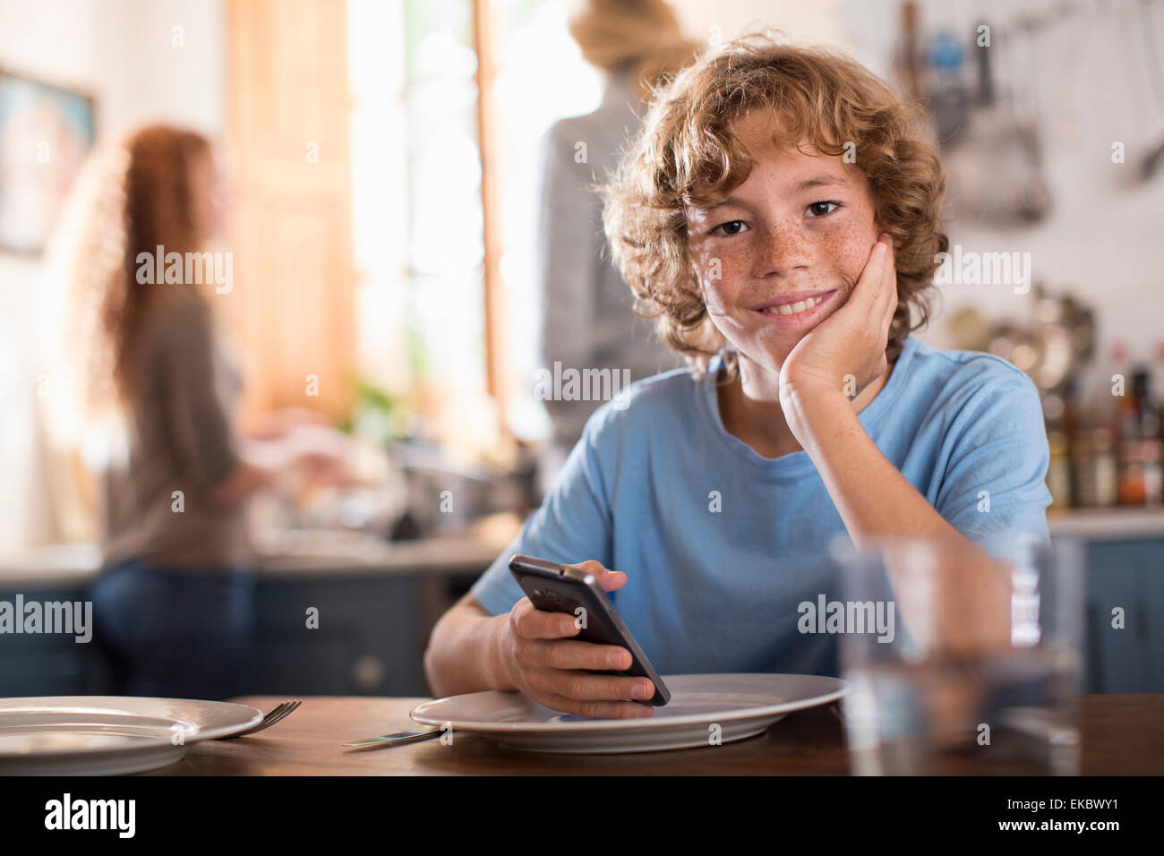 Teenage boy holding smartphone à table à manger Banque D'Images