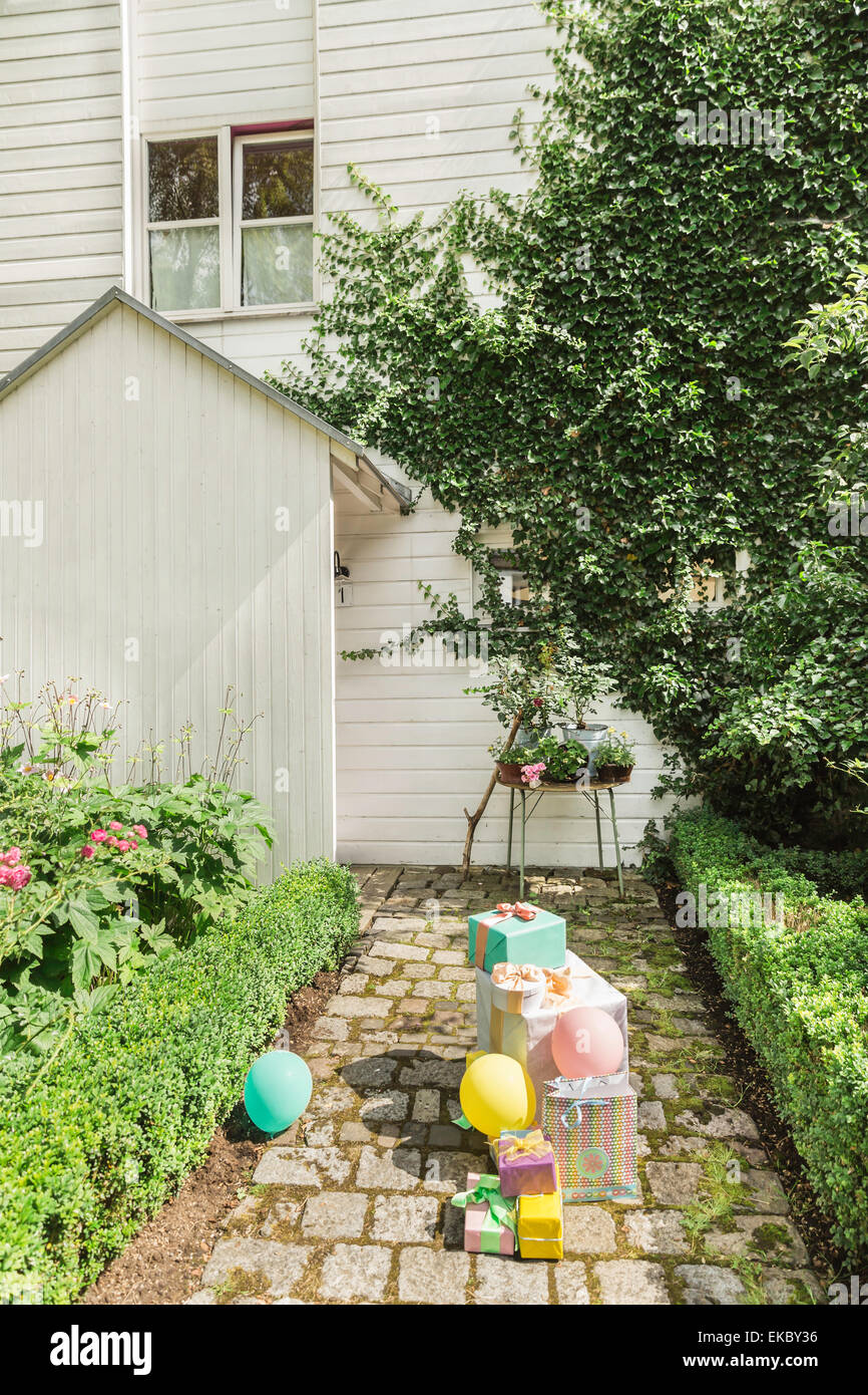 Des ballons et des tas de cadeaux d'anniversaire sur le chemin de jardin Banque D'Images