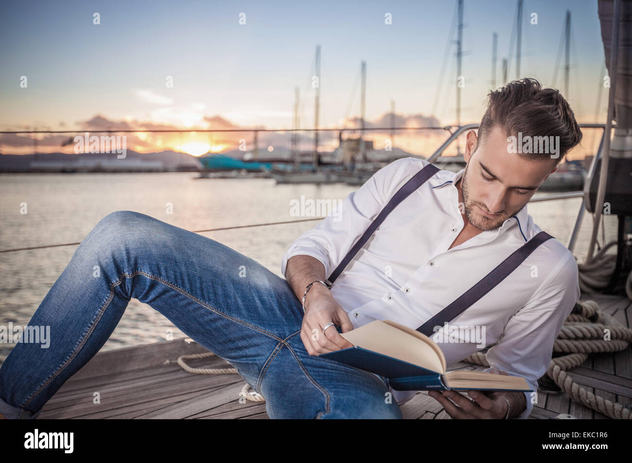 Jeune homme lecture le yacht, Cagliari, Sardaigne, Italie Banque D'Images