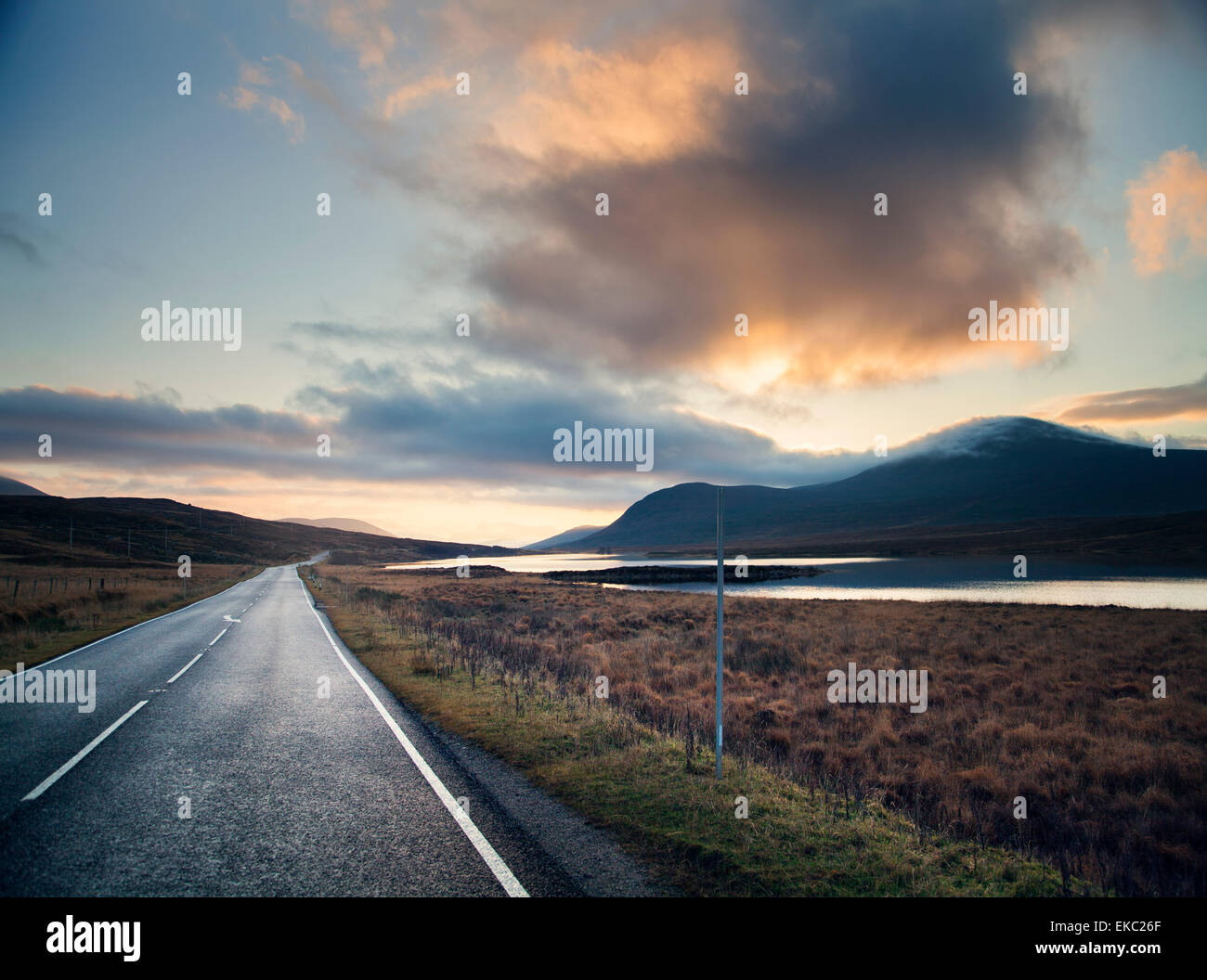 Vue de l'espace rural route au coucher du soleil, le loch Assynt, North West Highlands, Ecosse, Royaume-Uni Banque D'Images
