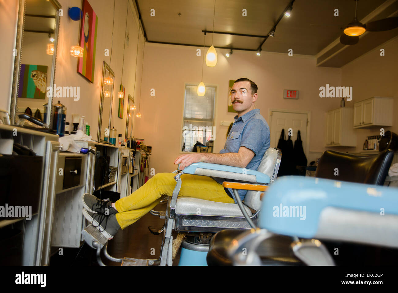 Jeune homme assis sur une chaise dans un salon de coiffure Banque D'Images