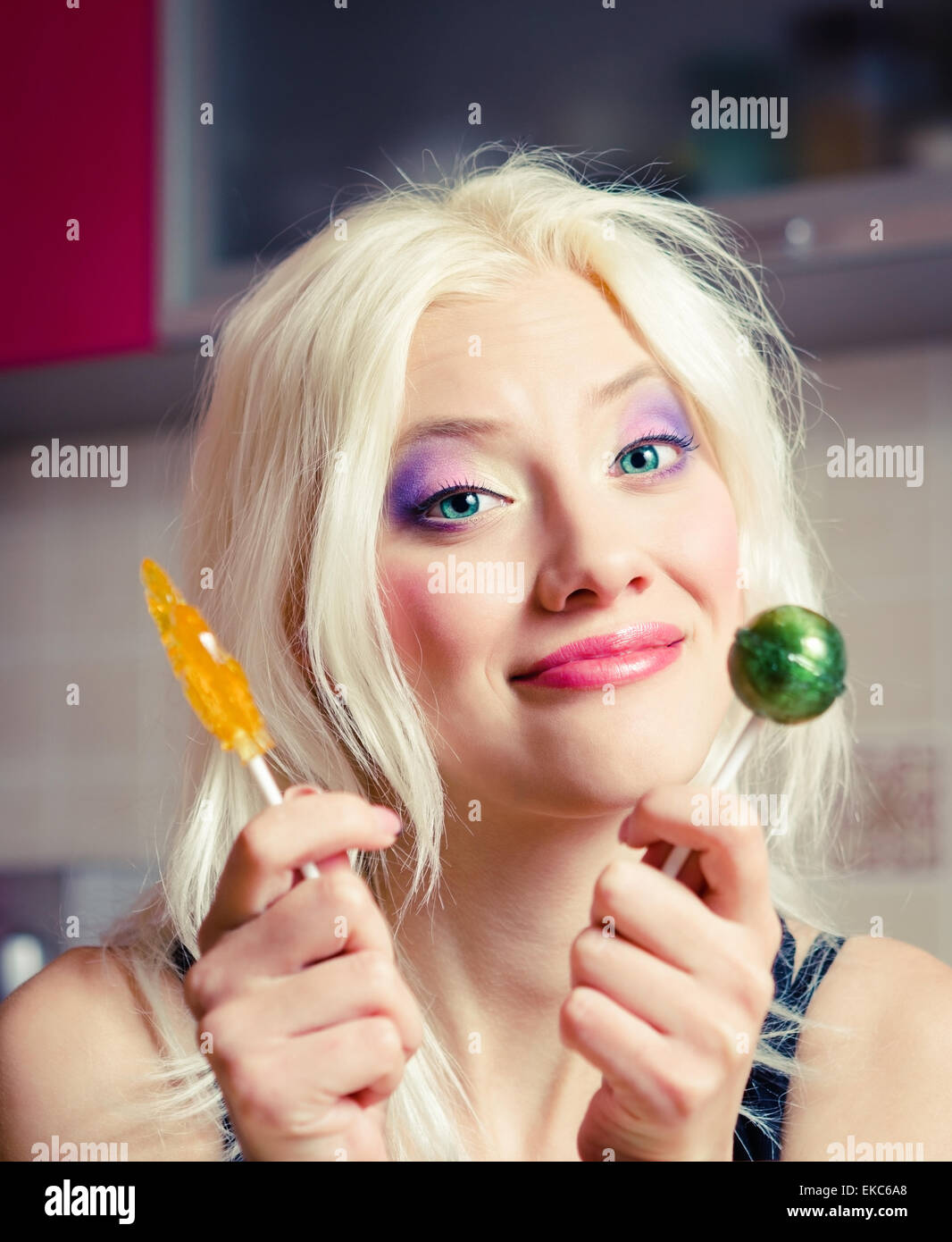 Portrait of smiling belle fille blonde avec deux bonbons dans les mains Banque D'Images