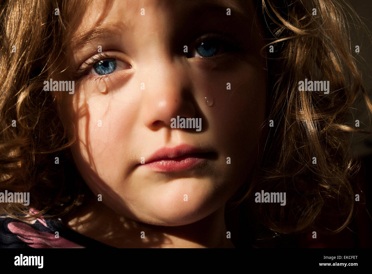 Portrait d'une fille triste avec des yeux bleus perçant pleurant Banque D'Images