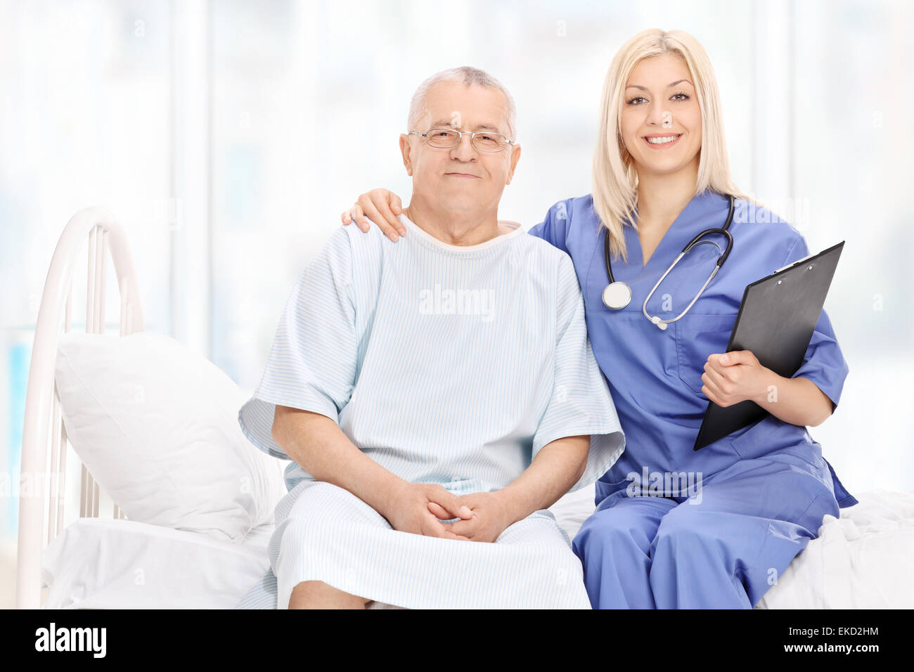 Jeune femme médecin et un patient mature posant assis sur un lit d'hôpital Banque D'Images